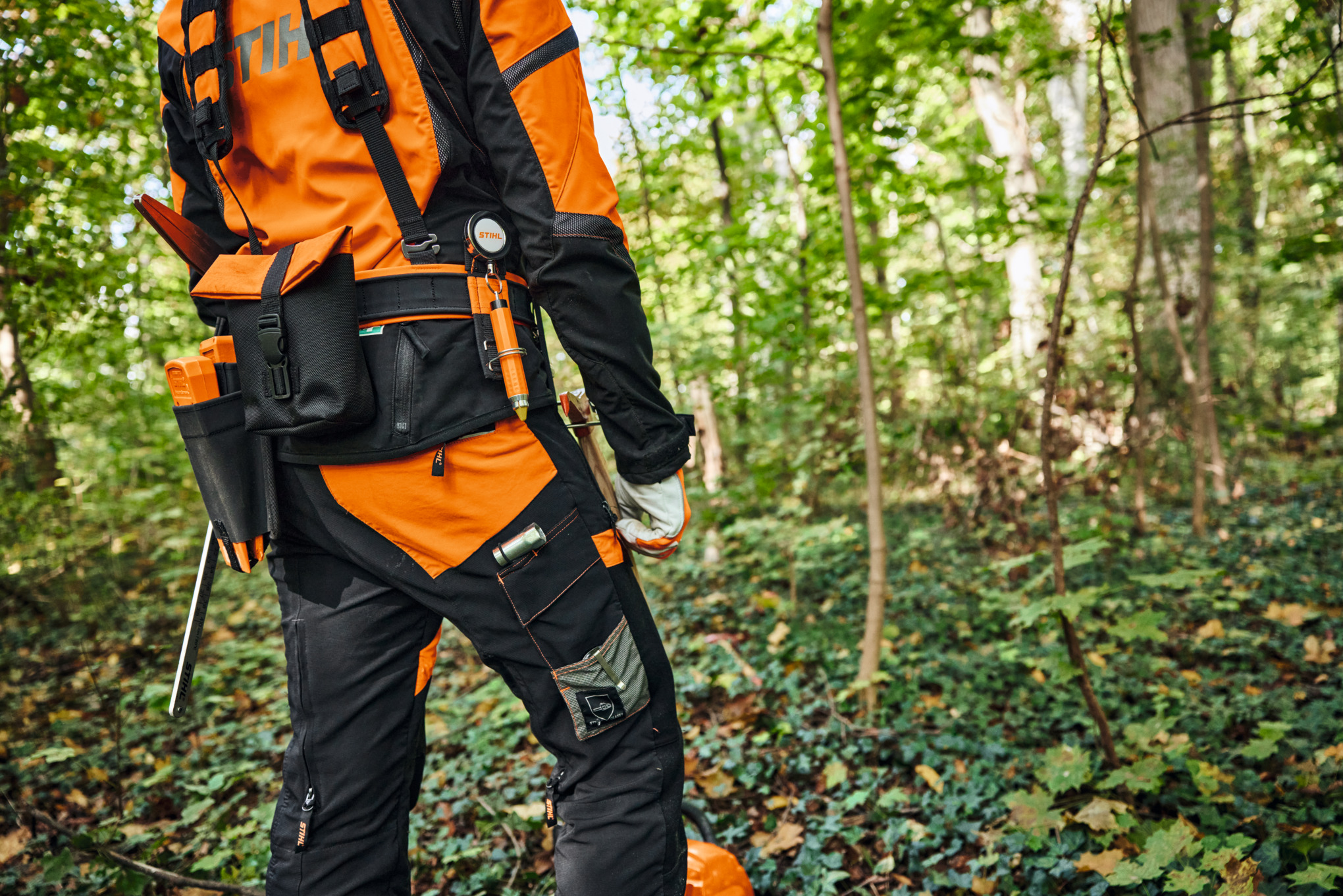 O persoană poartă echipament de protecție și sistemul modular de centuri STIHL ADVANCE X-Flex în pădure